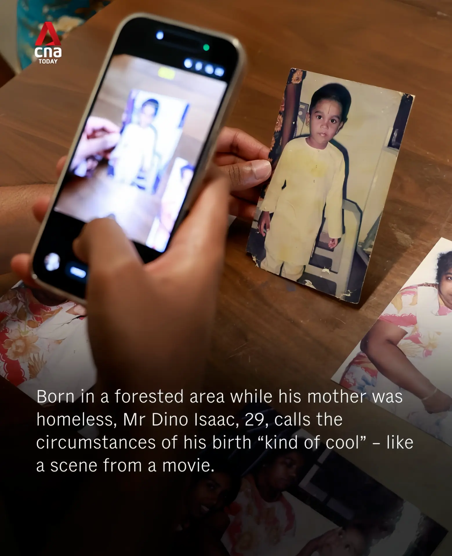 A hand holding a phone photographing an old childhood picture of Dino Isaac